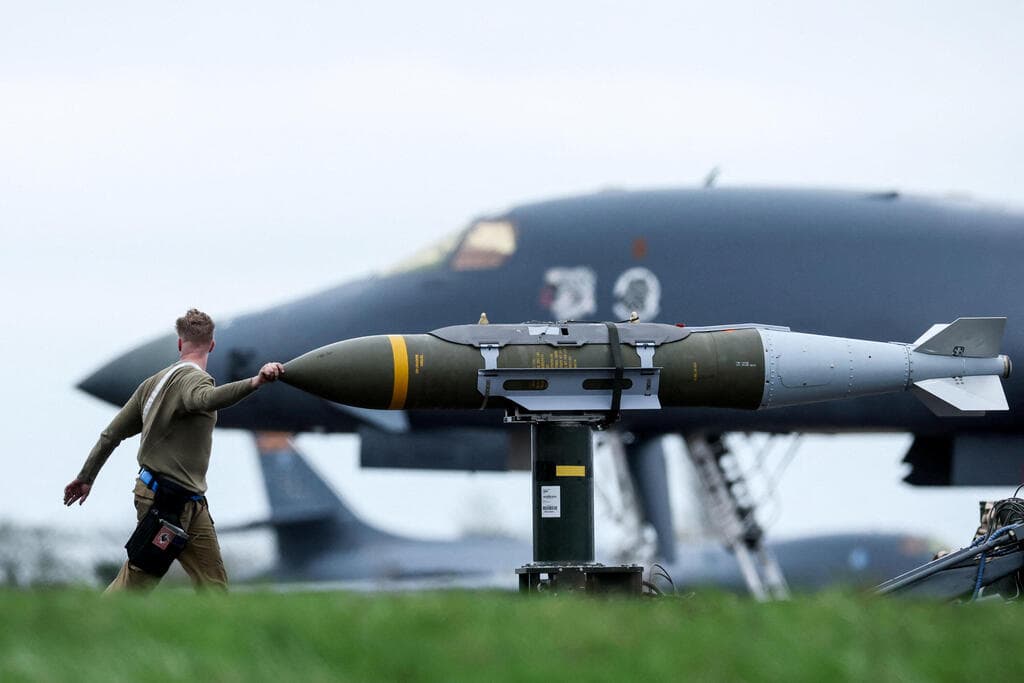 חייל אמריקני מכין פצצה חודרת בונקרים  JDAM לצד מפציצים מפציץ B-1B של חיל האוויר של ארה"ב לקראת הפצצות ב איראן ב בסיס אווירי ב פיירפורד בריטניה