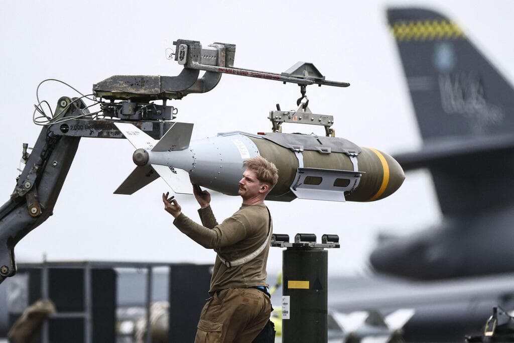 חייל אמריקני מכין פצצה חודרת בונקרים  JDAM לצד מפציצים מפציץ B-1B של חיל האוויר של ארה"ב לקראת הפצצות ב איראן ב בסיס אווירי ב פיירפורד בריטניה