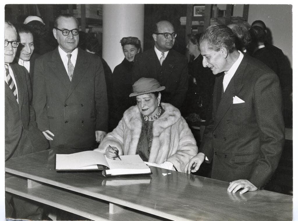 הלנה רובינשטיין חותמת בספר המבקרים בחנוכת הביתן, לצידה מנהל המוזיאון אויגן קולב, 1959
