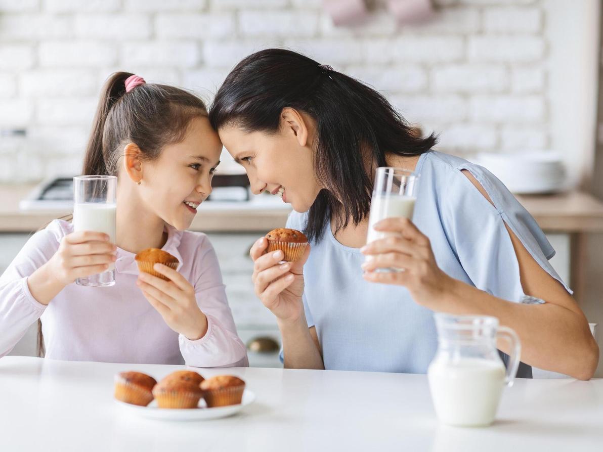אמא ובת שותות חלב ואוכלות עוגיות מאפינס