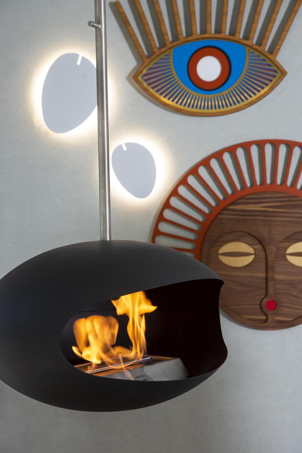 קמין תלוי ולצדו מסכות משובבות לב של האמן צחי נבו (צילום: עידן גור) דירת דופלקס-גן בתל אביב, עיצוב: מיטל צימבר