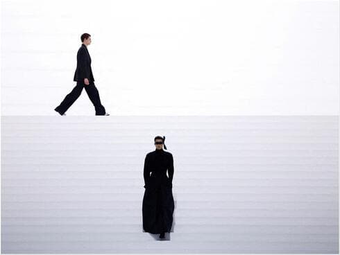 דוגמן חמוש מסכת עיניים ומעיל שחור ארוך פתח את תצוגת האופנה של דיור בעיצוב קים ג'ונס דוגמן חמוש מסכת עיניים ומעיל שחור ארוך פתח את תצוגת האופנה של דיור בעיצוב קים ג'ונס