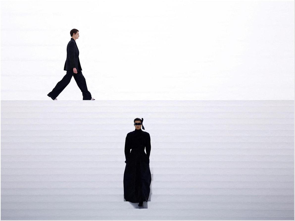 דוגמן חמוש מסכת עיניים ומעיל שחור ארוך פתח את תצוגת האופנה של דיור בעיצוב קים ג'ונס (צילום: REUTERS/Sarah Meyssonnier) דיור, תצוגת סתיו-חורף 2025-26 בשבוע האופנה לגברים בפריז