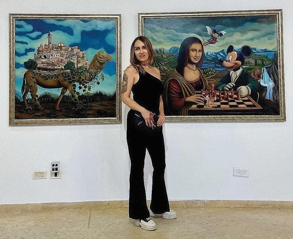 לדה לפידוס על רקע יצירותיה. "ביום שבו גיליתי את הקנווס השתנה עולמי, לא יכולתי להפסיק לצייר""