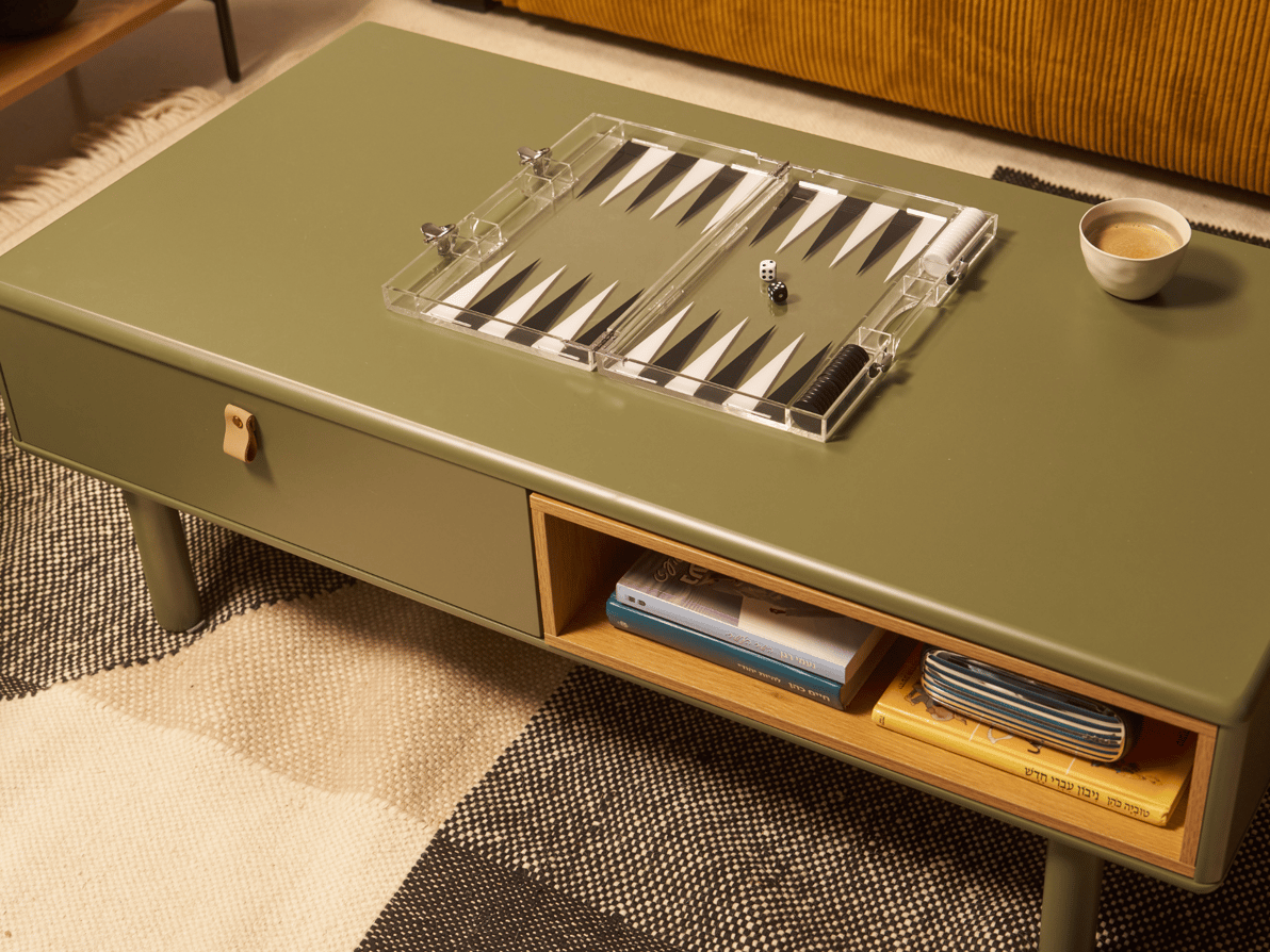 שולחן סלון ירוק דגם NEST של חברת נאפו ועליה שש-בש שקוף שנרכש בלונדון