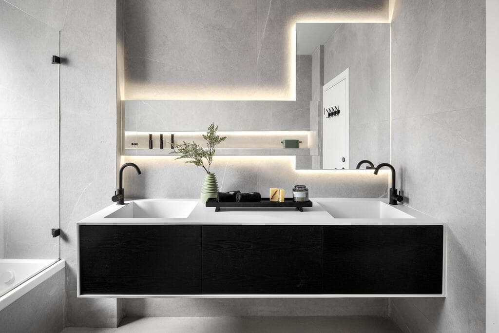 עיצוב חדר רחצה מודרני בהיר בחיפוי דמוי אבן עם מראות א-סימטריות. עיצוב: שירי שלום