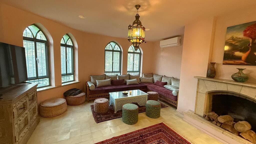 קמין שיוצר חום וביתיות, ספות והמון כריות. הסלון (צילום: חיים ברגיג) בית השנטי החדש, עין הכרם, ירושלים