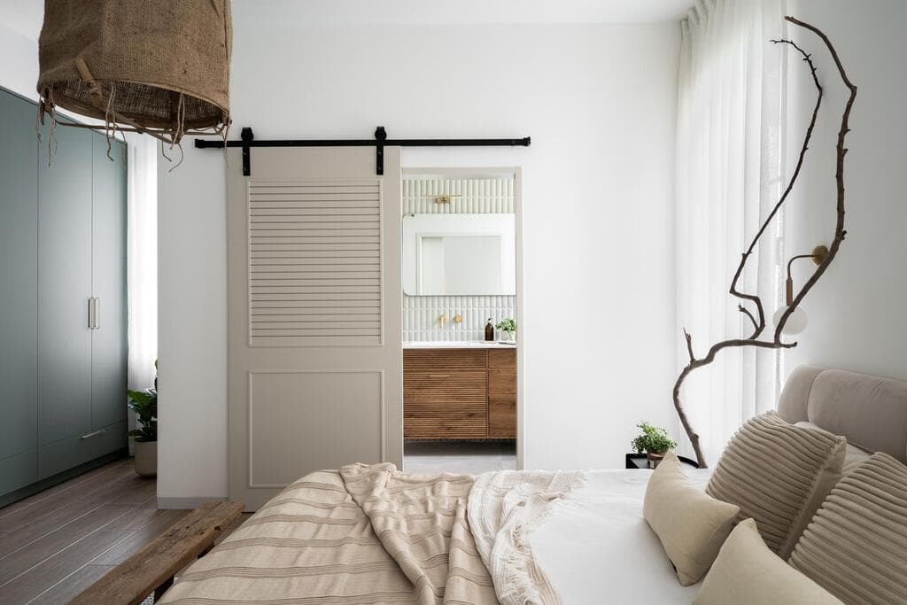 הענף שולב לצד המיטה, ומבעד לדלתות האסם נמצא חדר הרחצה (צילום: קרין רבנה) בית פרטי במושב אשבול ליד נתיבות. עיצוב: ליאת שעיה