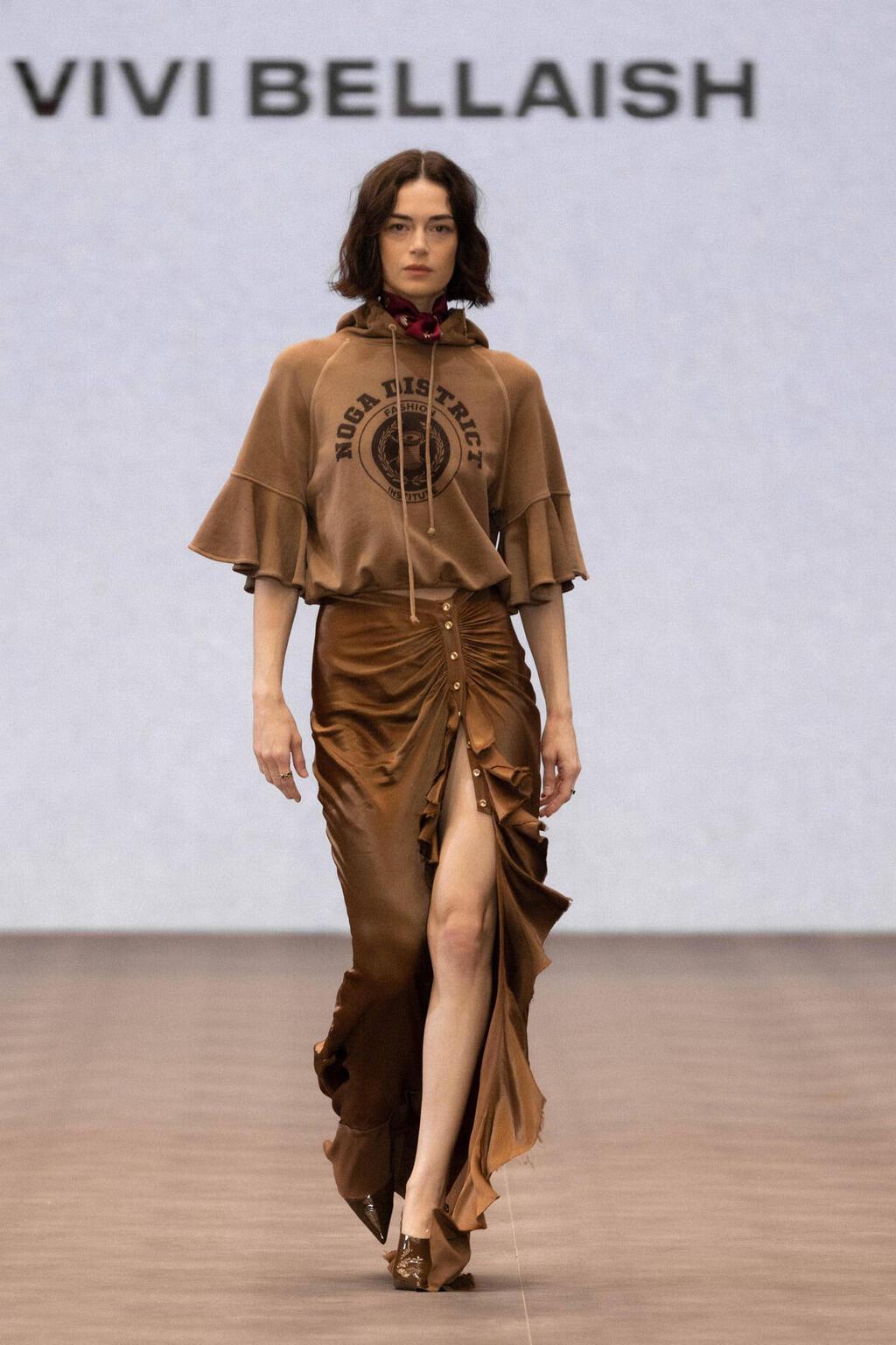 שילוב בין סווטשירט עם הדפס שמה של שכונת נגה ביפו לחצאית משי אלכסונית. ויוי בלאיש (צילום: עומרי רוזנגרט) התצוגה של ויוי בלאיש בשבוע האופנה תל אביב, 2025