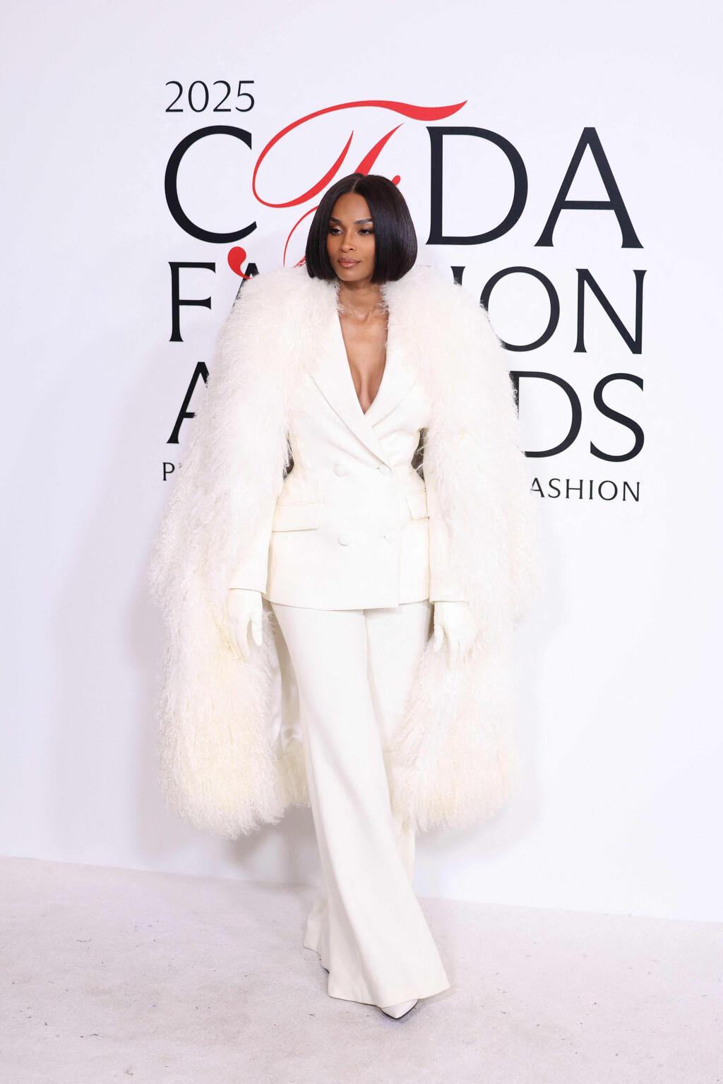 קיארה בחליפה לבנה עם מעיל נוצות תואם בעיצוב סרג'יו הדסון (צילום: CHARLY TRIBALLEAU/AFP) קיארה בטקס פרסי האופנה של ה-CFDA ל-2025