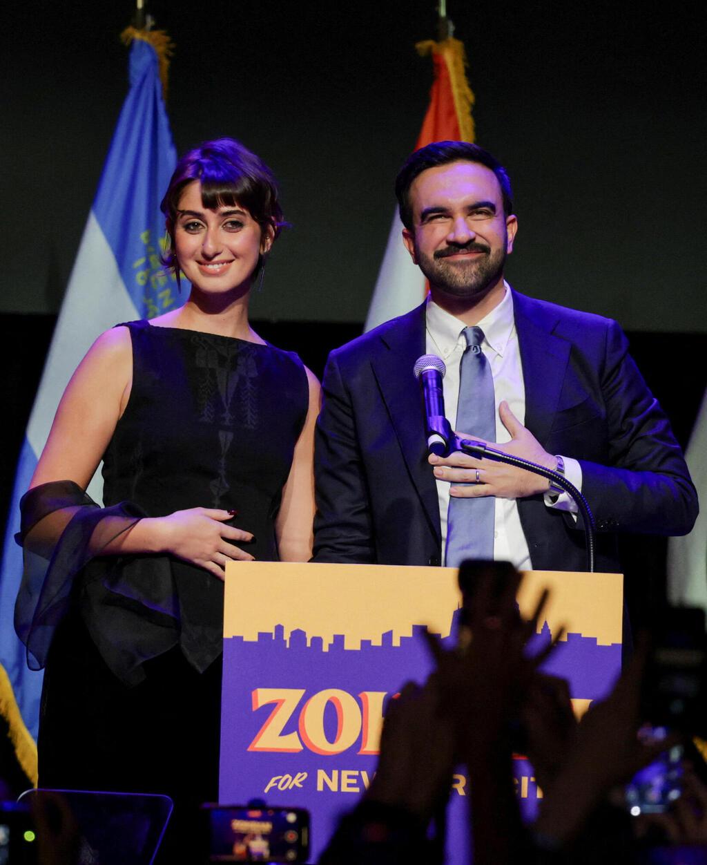 ראמה דוואג'י בחולצה של זאיד חיג'אזי וחצאית של אולה ג'ונסון (צילום: REUTERS/Jeenah Moon) ראמה דוואג'י וזוהרן ממדאני לאחר הניצחון בבחירות לראשות העיר ניו יורק, 2025
