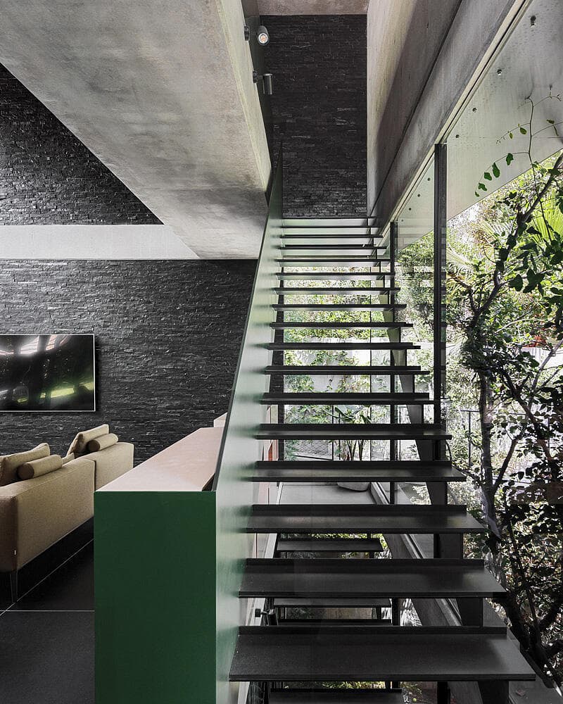 המדרגות בשחור עם מעקה ירוק, כשהאור חודר דרכן (צילום: שי אפשטיין) וילה בשרון, אדריכלות ועיצוב: נורית בן יוסף