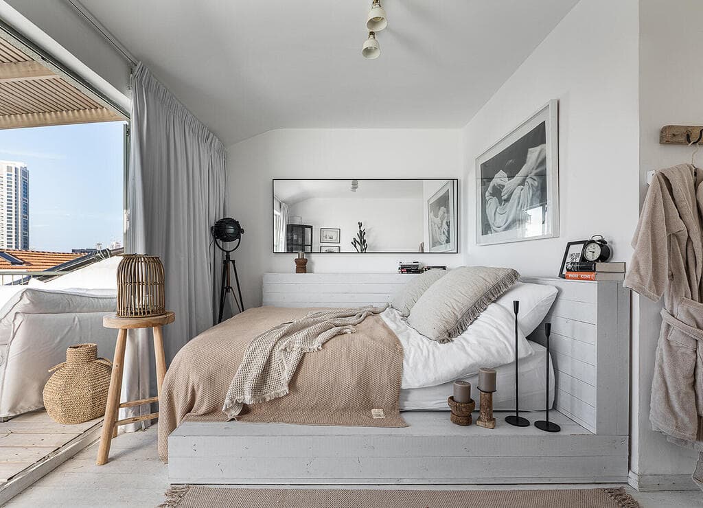 המיטה על במת עץ ויש יציאה למרפסת (צילום: גדי יוסף) בית בנווה צדק, עיצוב: נעמה רודין אשר