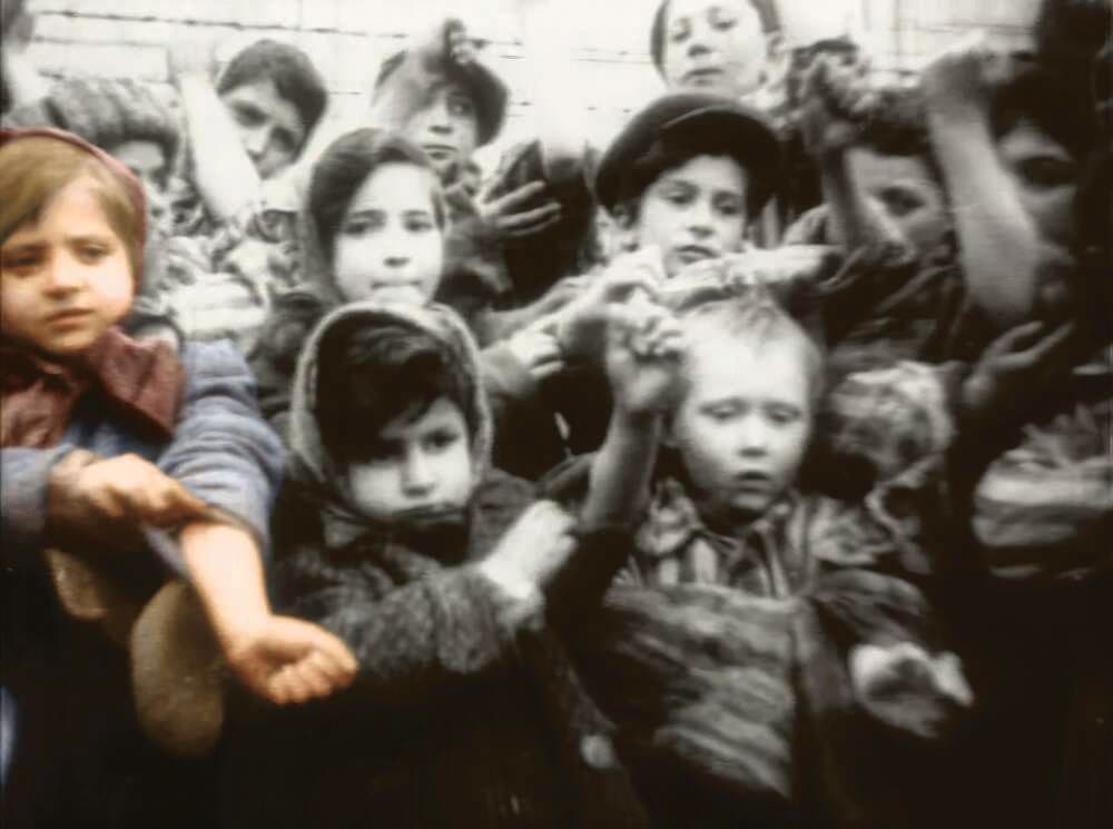 טובה )בצבע( וילדים ניצולים אחרים מציגים את המספר שקועקע על ידיהם בפני  צלם סובייטי, ימים אחדים לאחר שחרור אושוויץ־בירקנאו, ינואר 1