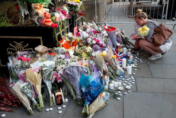 מנחמים מניחים פרחים ונרות לזכר הנרצחים במנצ'סטר, לפני שבע שנים