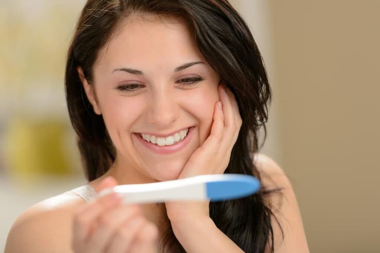 אישה מחייכת עם בדיקת היריון