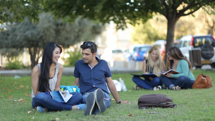 גבר ואישה יושבים על דשא ובידיהם ספרי לימוד