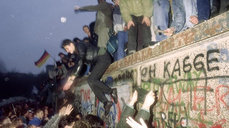 אנשים במערב ברלין מול שבר בחומה ומהצד השני חיילים ממזרח ברלין