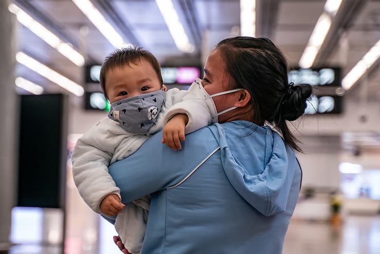 אישה עם תינוק בתחנת רכבת מסיכות 