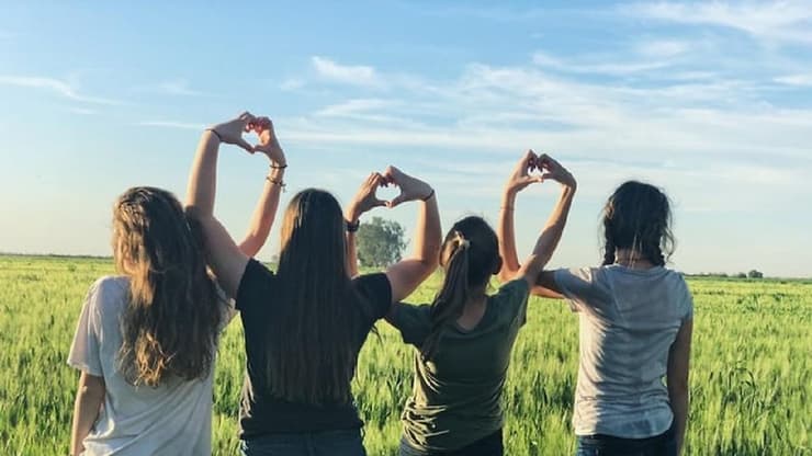 נערות עם הגב למצלמה נותנות ידיים שיוצרות לבבות 
