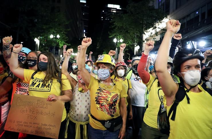 ארה"ב מחאת ג'ורג' פלויד פורטלנד אימהות בצהוב מפרידות בין מפגינים ל כוחות הביטחון