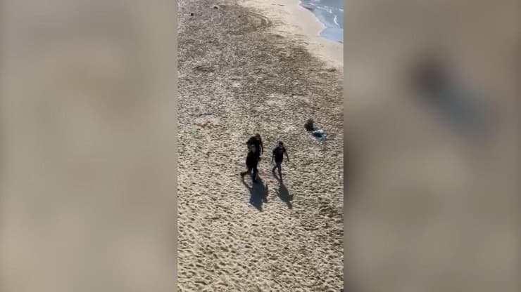 רוחצים בחוף הים בורחים מהשוטרים שאוכפים את הסגר