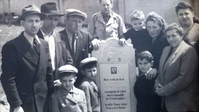 יוני 1948 , משפחת אייזנברג וברנדספיגל מתאספות סביב מצבתו של אברהם אייזנברג במחנה העקורים חליין באוסטריה. אייזנברג, אביו של ניצול השואה ישראל "סשה" אייזנברג, נפטר בתאונת דרכים זמן קצר לאחר מלחמת העולם השנייה.