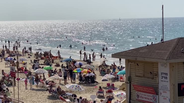 הרבה רוחצים בחוף הים בתל אביב