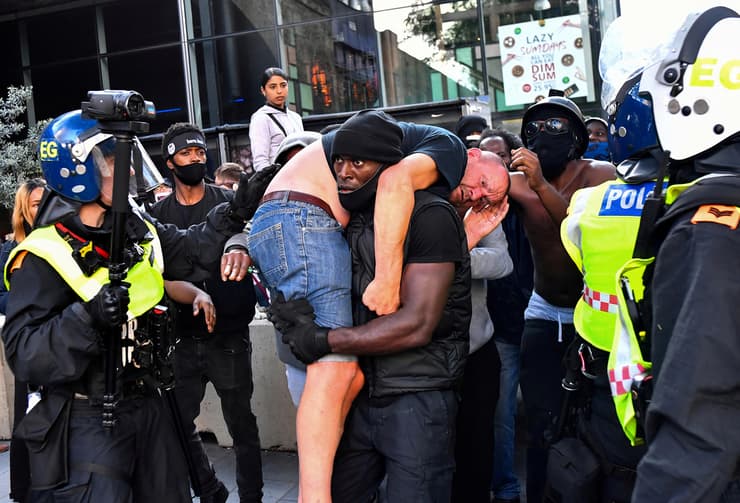 תמונות השנה של רויטרס 2020 המפגין פטריק הצ'ינסון מחלץ מפגין פצוע מהמחנה הנגדי בהפגנת black lives matter לונדון 13 יוני