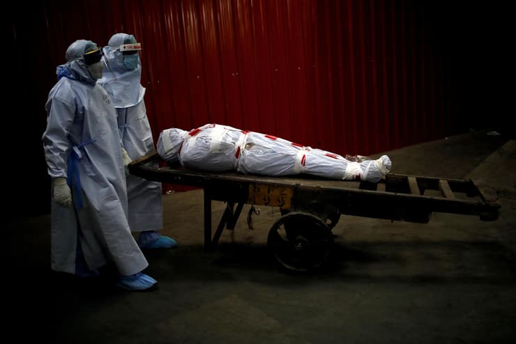 תמונות השנה של רויטרס 2020 עובדי רפואה סוחבים גופת מת מקורונה בדרך ל שריפה ב הודו 4 יוני