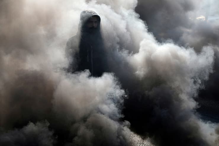תמונות השנה של רויטרס 2020 מפגין ב עיראק מבעד ל עשן מחאה נגד הממשלה 20 ינואר