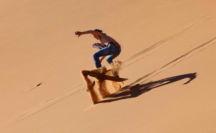תייר מבצע סקי חול במדבריות דובאי