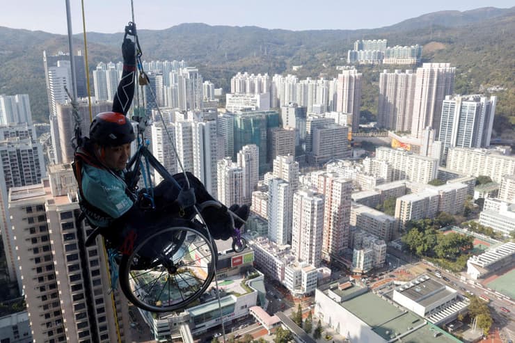 לאיי צ'י-ואיי מטפס פראלימפי מטפס על חבל במעלה מגדל גורד שחקים ב הונג קונג עם כיסא גלגלים