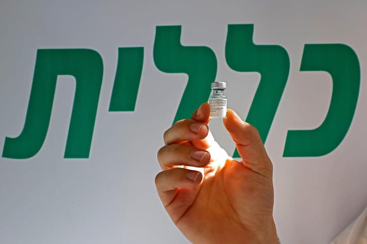 לוגו קופת חולים כללית עם בקבוקון חיסון ב מרכז חיסון חיסונים ב פתח תקווה 1 בפברואר
