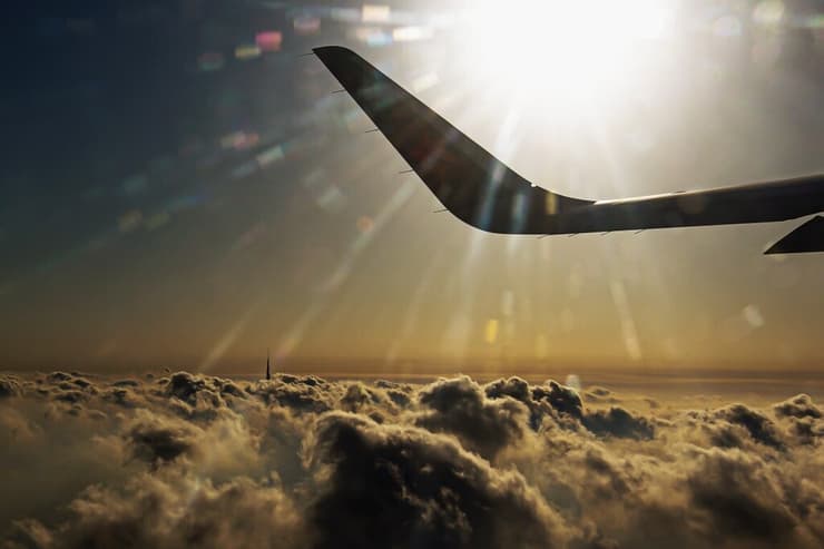 המראה מדובאי מהחלון האחורי. הווינגלט (יתד הגהה) של מטוס ישראייר מעל העננים וברקע מבצבץ הבורג' חליפה