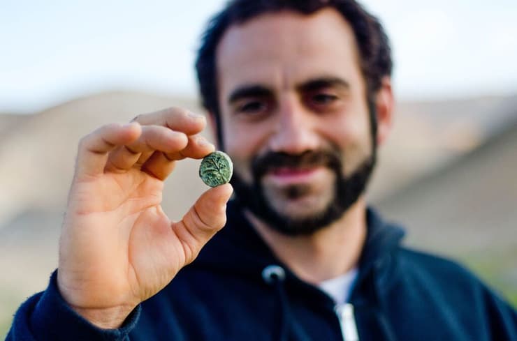 ארכיאולוג חגי המר מחזיק מטבע בר כוכבאי שנמצא במדבר