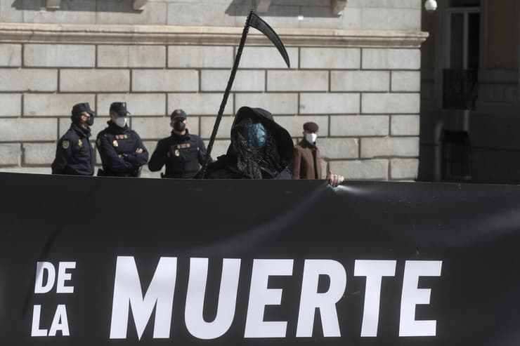 אחד ממתנגדי החוק מחופש למלאך המוות מול בניין הפרלמנט במדריד   