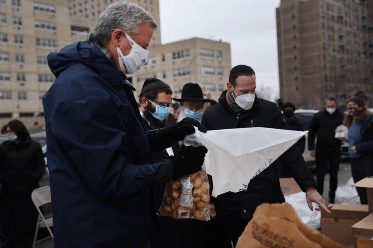 ראש עיריית ניו יורק ביל דה בלאזיו מסייע באריזת מצרכים לנזקקי הקהילה היהודית בעיר לקראת פסח