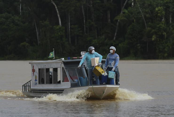 צוות רפואי שט ב נהר אמזונס ב ברזיל בדרך לקהילת סנטה רוזה חיסון קורונה