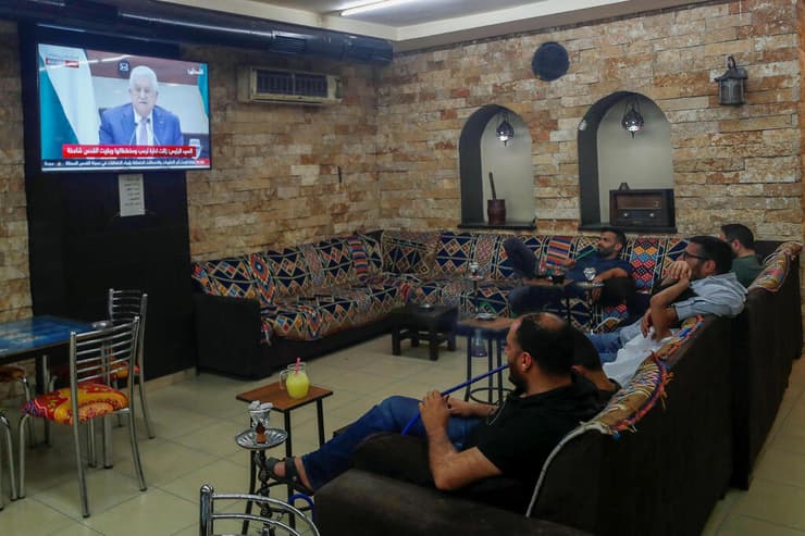 יושבים בית קפה ברמאללה צופים בנאום של אבו מאזן