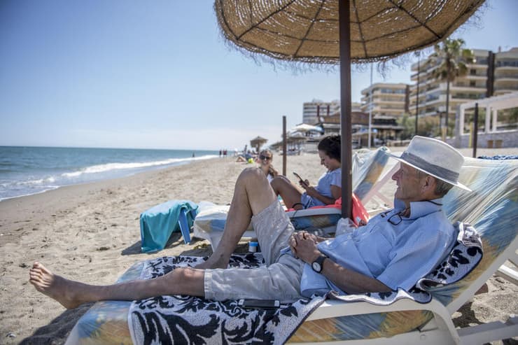 תיירים בריטים מבלים בחוף בספרד. השמיים נפתחים בהדרגה  