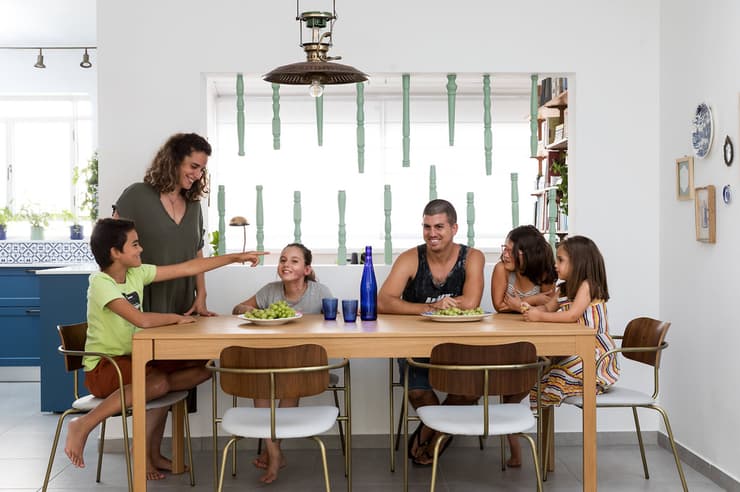 המעצבת דבורי פריד טובול עם בני המשפחה סביב שולחן האוכל. עיצוב: דבורי פריד טובול. מטבחי רגבה. 