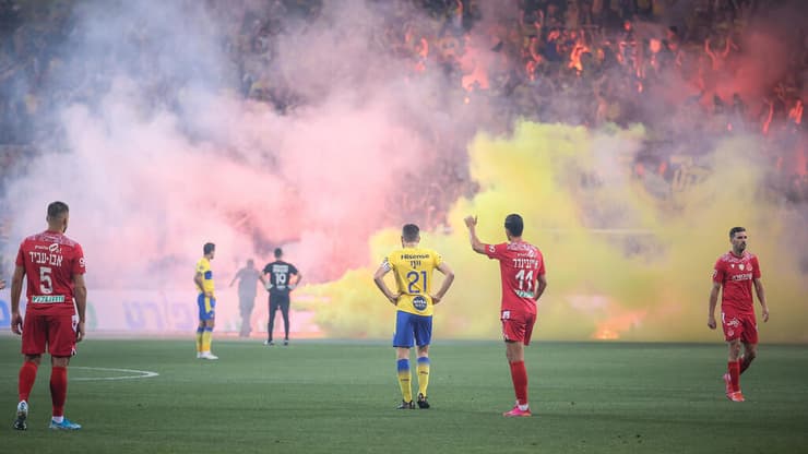 האבוקות והחזיזים שהושלכו לכר הדשא בדרבי התל-אביבי האחרון (צילום: עוז מועלם) ייני ואיינבינדר צופים באבוקות של אוהדי מכבי ת"א