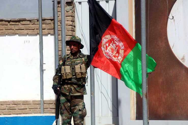 חייל אפגני מניף את דגל ארצו בבסיס שמסרו לידי האפגנים חיילים איטלקים שהתפנו 