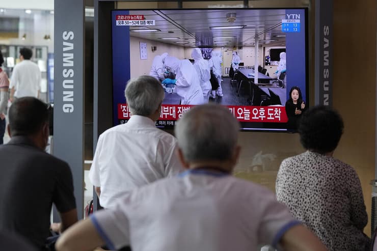 דרום קוריאנים צופים בטלוויזיה באנשי רפואה ב משחתת ספינה של הצי של דרום קוריאה שם נרשמה בהתפרצות קורונה
