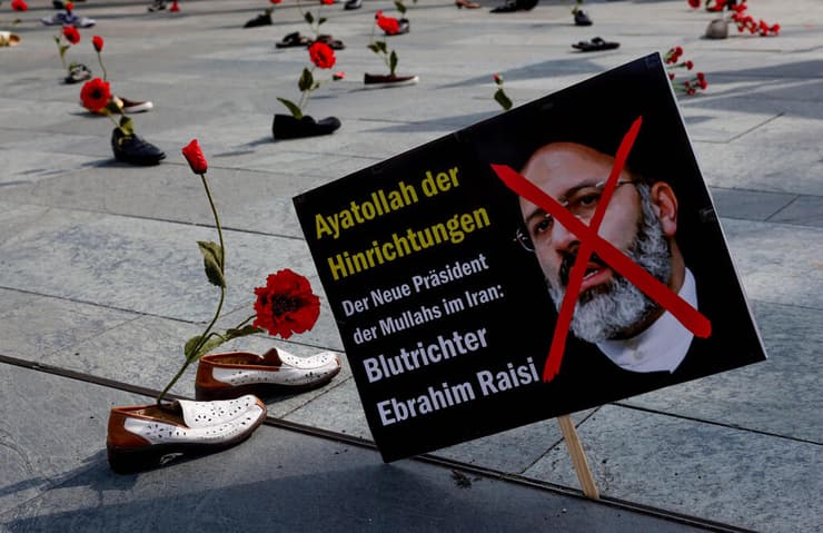שלט מחאה ב ברלין נגד השבעת נשיא איראן איברהים ראיסי שבו כתוב "האייתולה של ההוצאות להורג, הנשיא החדש של המולות של איראן, שופט הדמים איברהים ראיסי"