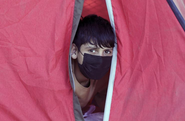 250,000 אלף פליטים בתוך שלושה חודשים. ילד מציץ מתוך אוהל בקאבול      