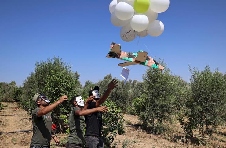 פלסטינים מפריחים בלונים עם תמונות הרוגים מהעימותים ומסרי איום