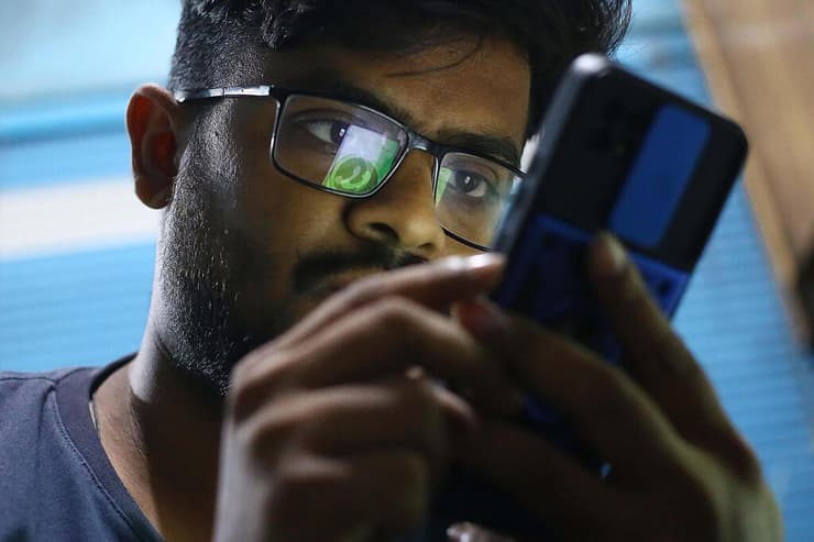 גבר בפקיסטן בודק את הווטסאפ בפלאפון בזמן התקלה