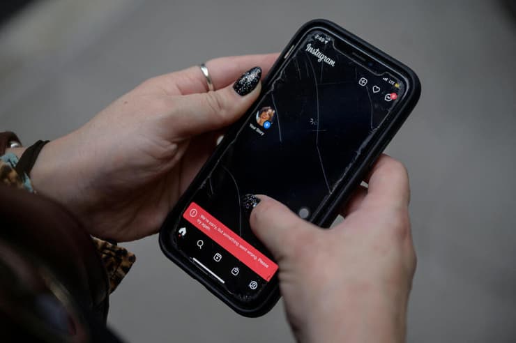 אישה מניו יורק בודקת בפלאפון את חשבון האינסטגרם שלה בזמן התקלה